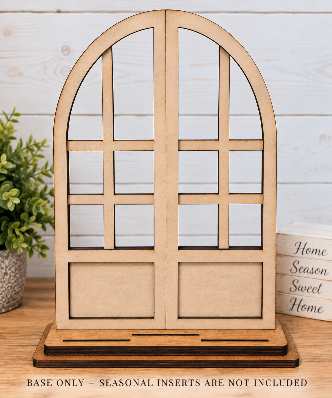 Laser-cut light natural wood arched window display stand on a wooden base. Text at the bottom reads 'BASE ONLY - SEASONAL INSERTS ARE NOT INCLUDED'.