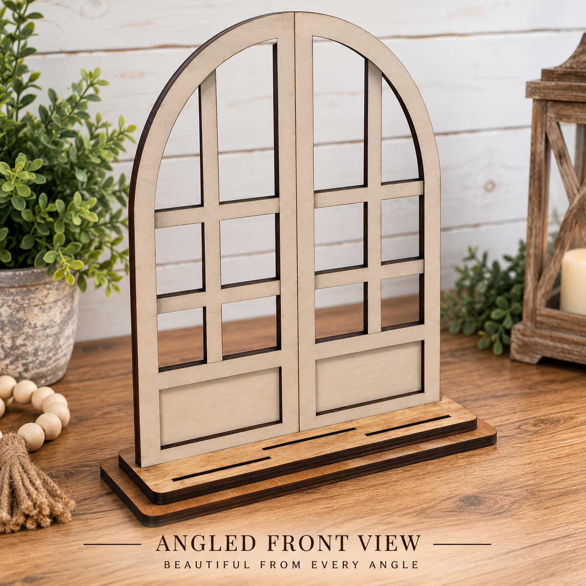A laser-cut wooden display stand shaped like an arched window with multiple panes. Text at the bottom reads 'ANGLED FRONT VIEW' and 'BEAUTIFUL FROM EVERY ANGLE'